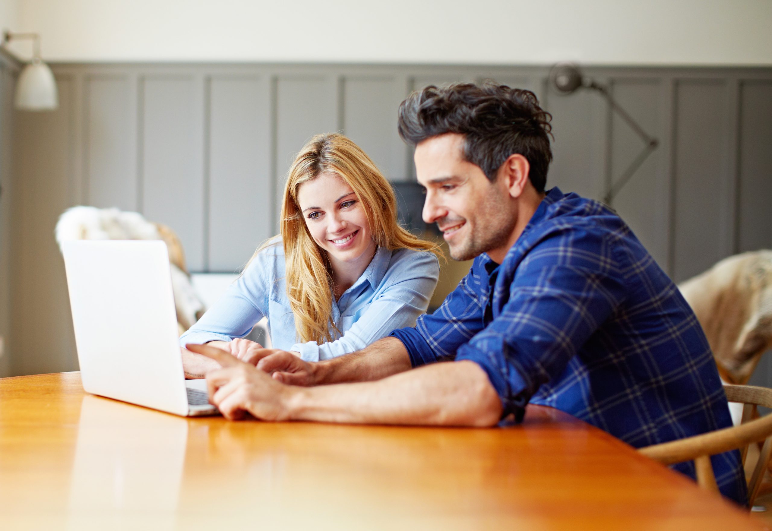 Young man and woman sitting at a table working on one laptop together