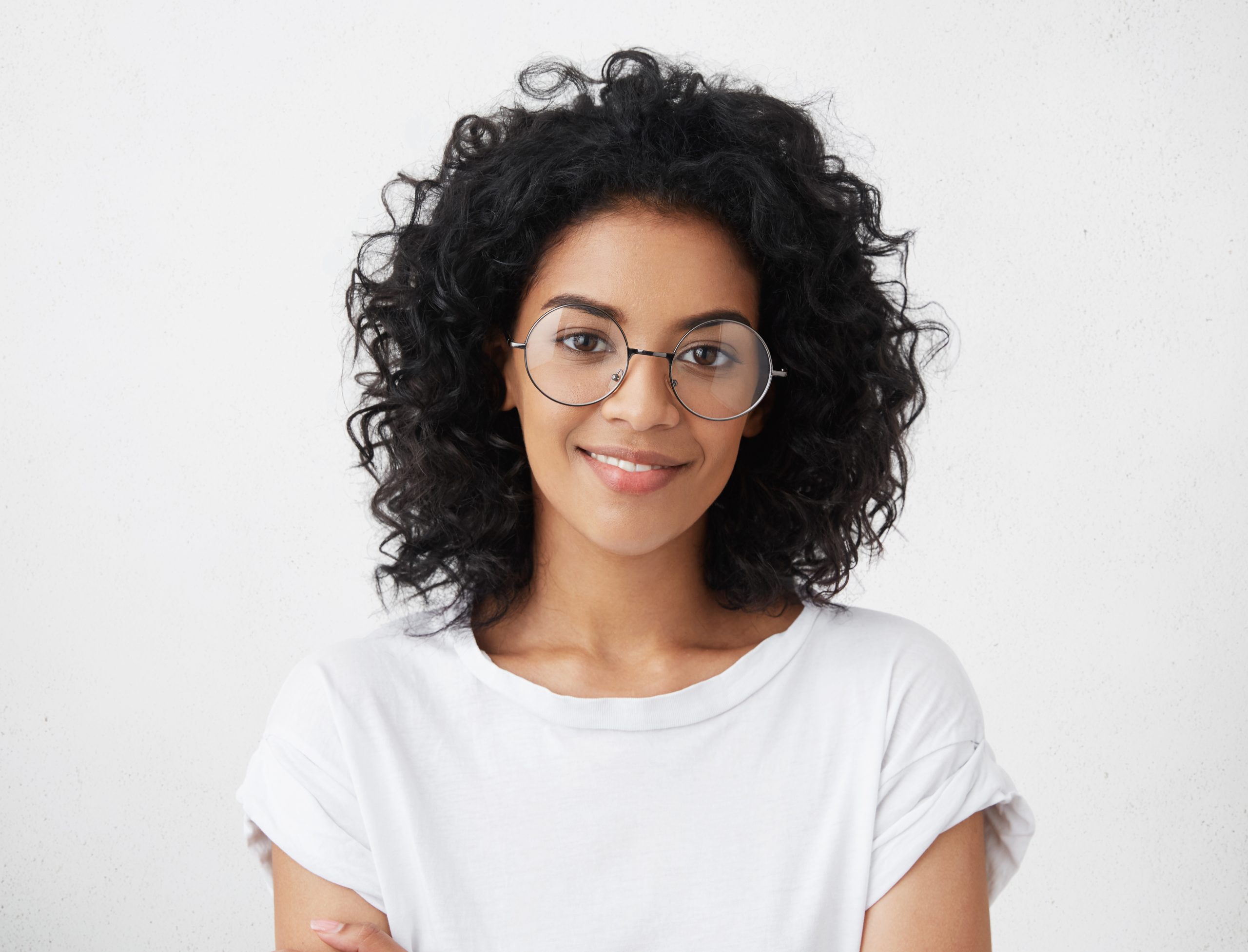 Portrait of a smiling woman with curly dark hair and glasses isolated on white background